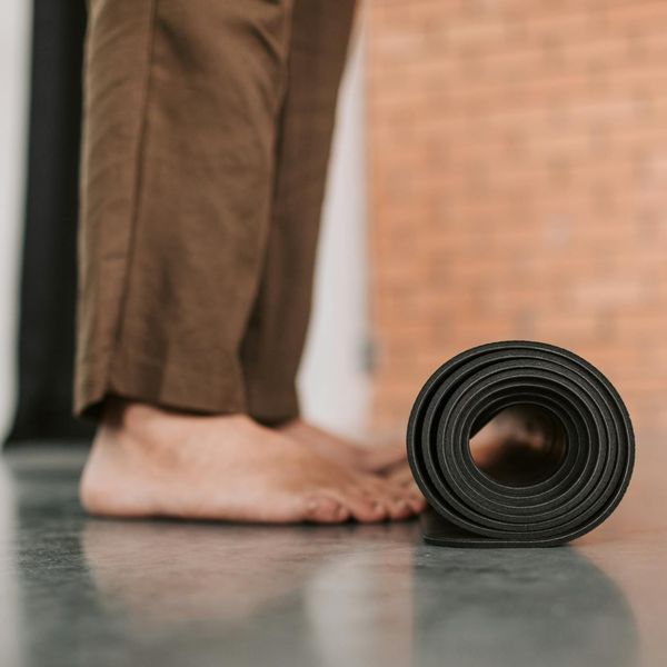 A person rolling out a yoga mat, preparing for their first practice.